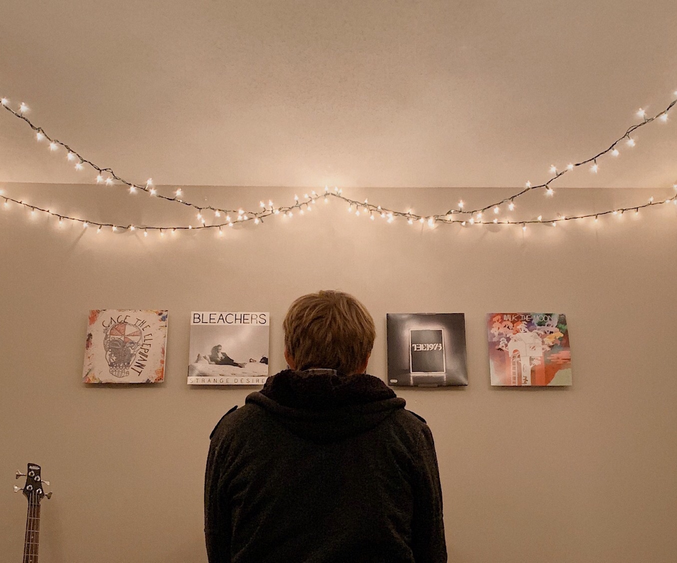 Person viewing four photographs beneath strings of Christmas lights