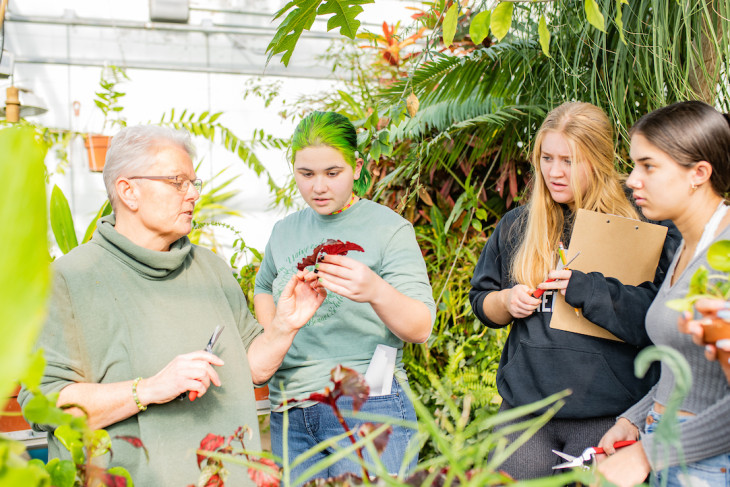 Professor in greenhouse with students