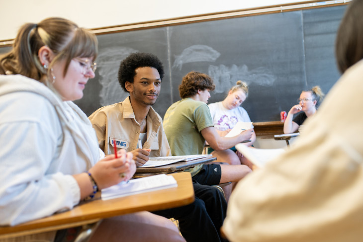 Students sitting at desks, listening intently, in a classroom