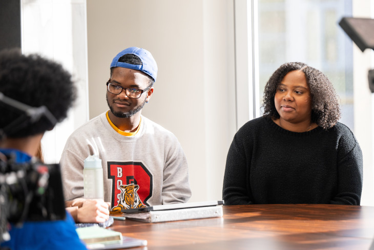 Two students sit at a table listening intently