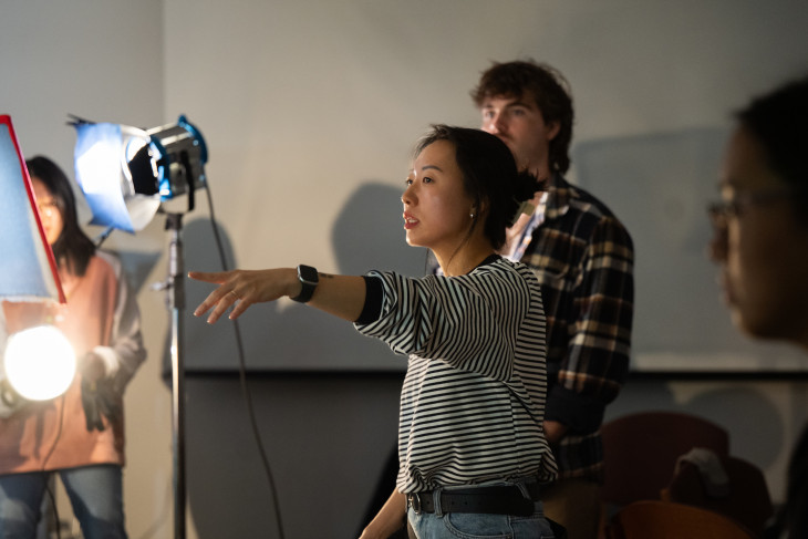 Student directing a video with 3 peers behind her