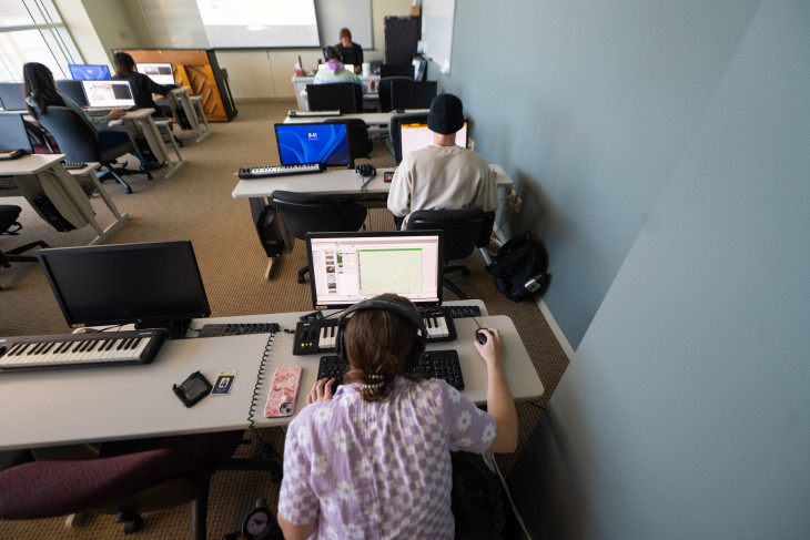 Students on computers with keyboards and instruments besides them