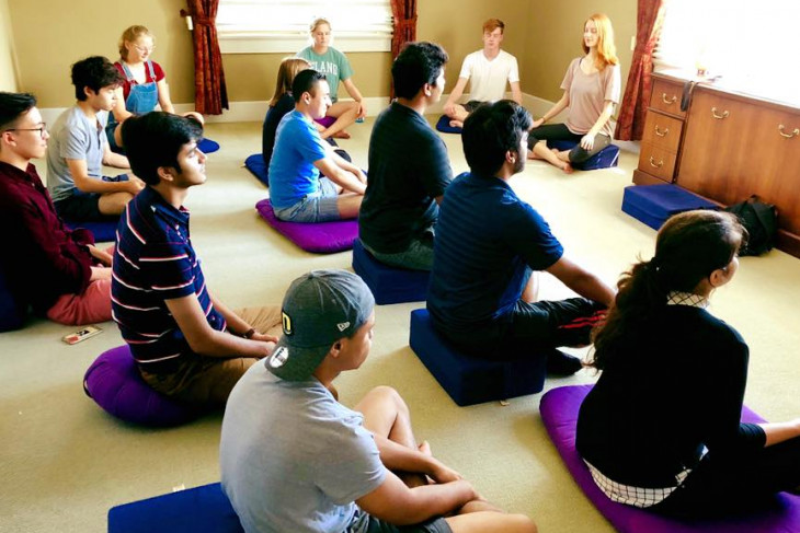 meditation club meeting. students sitting on yoga mats