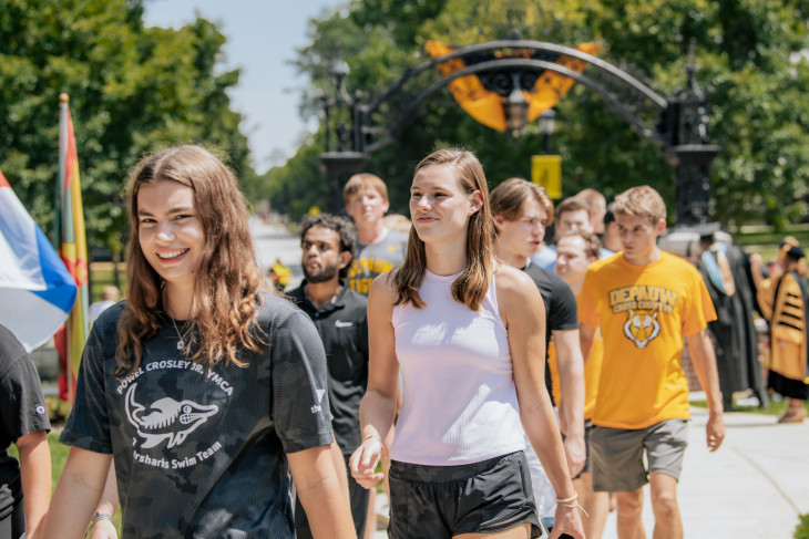 Students smiling as they walk through DePauw's iconic arch