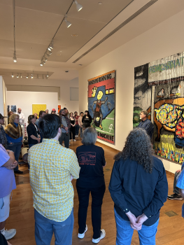 The artist standing in a room of people talking about his exhibition 