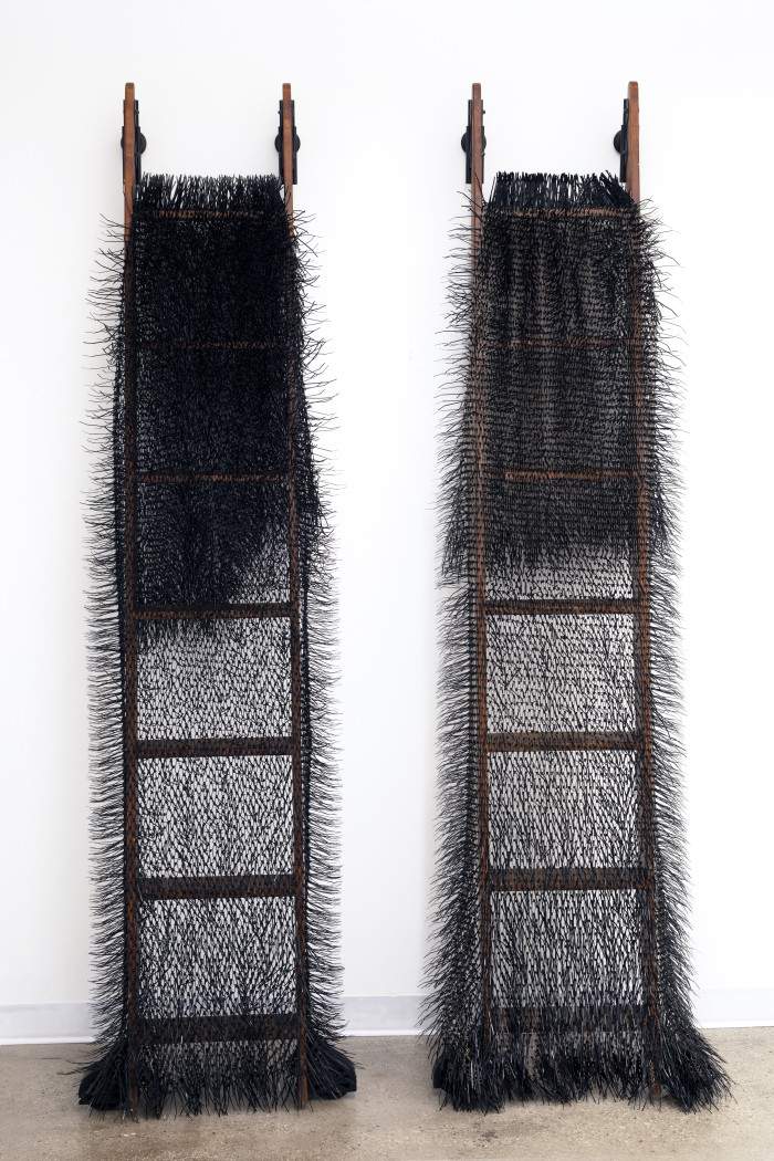 Black yarn fibers draped on two dark ladders